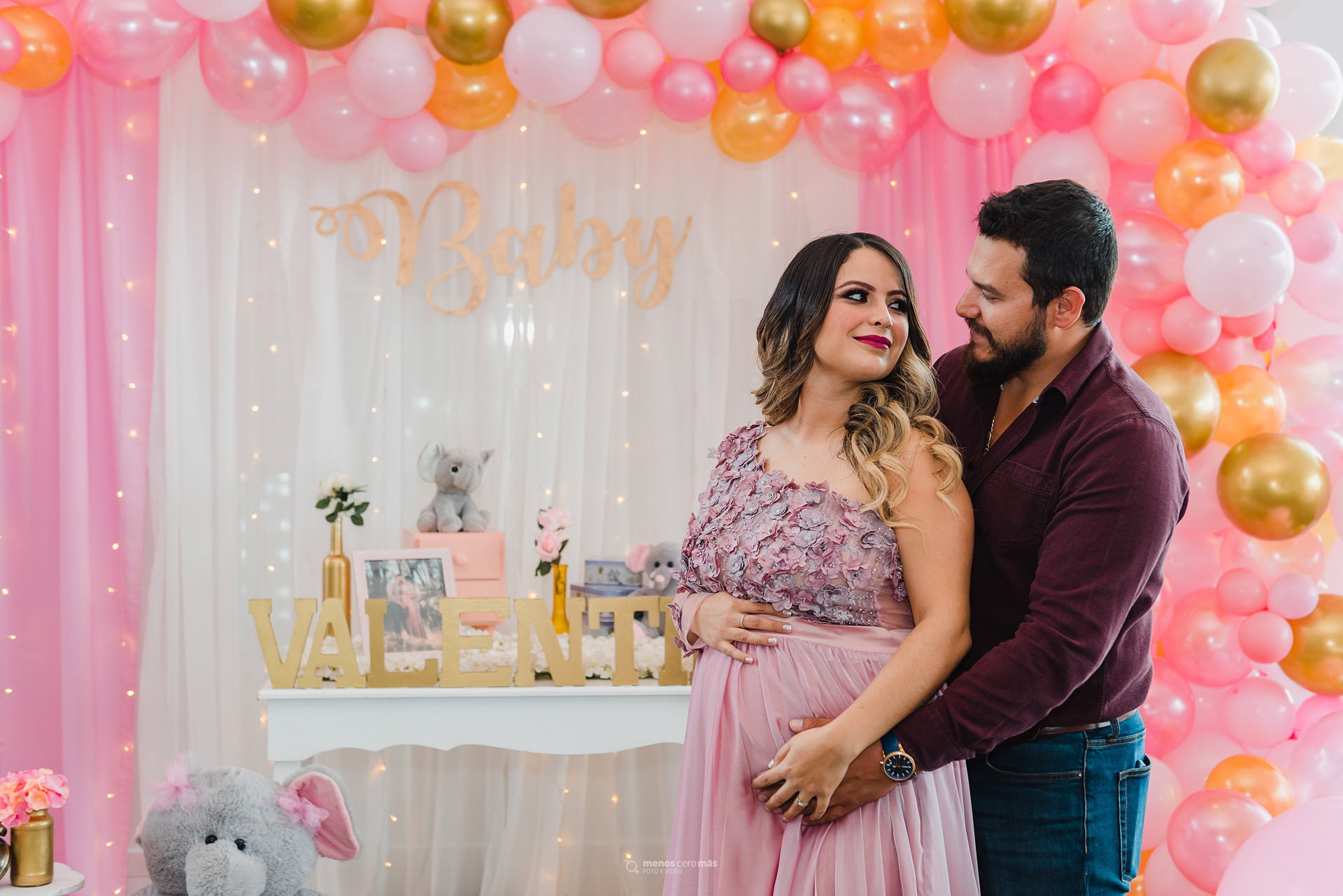 En la foto Valeria y su esposo comparten un tierno abrazo frente a la decoración de su babyshower en lux eventos, Monterrey.