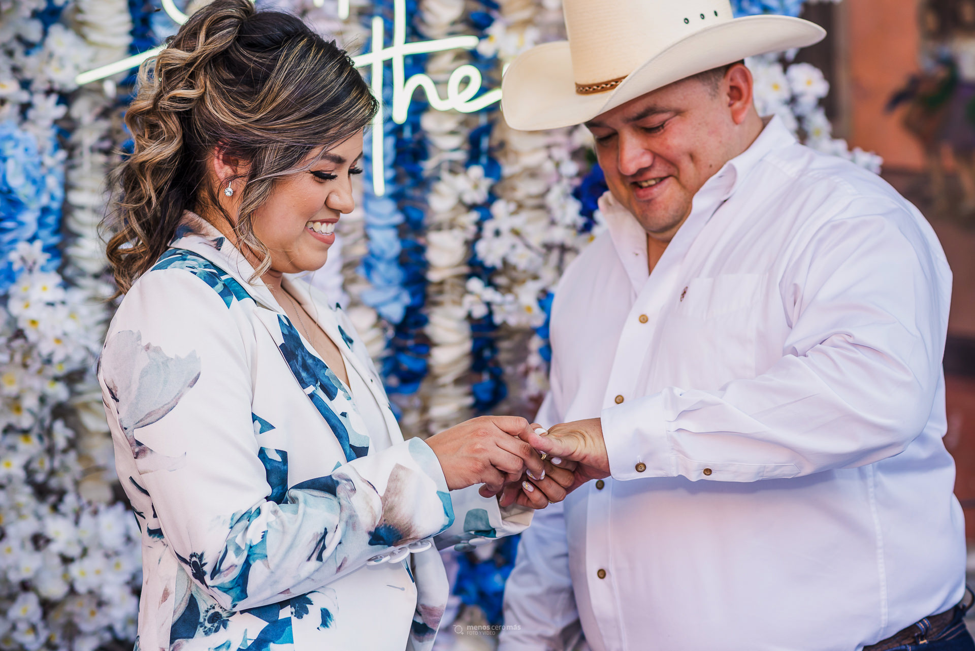 Compromiso eterno: Un intercambio de anillos lleno de amor y emoción en La Hacienda, durante la boda Los novios se miran a los ojos mientras la novia coloca el anillo al novio, sellando su futuro juntos, fotografía por "menosceromás".