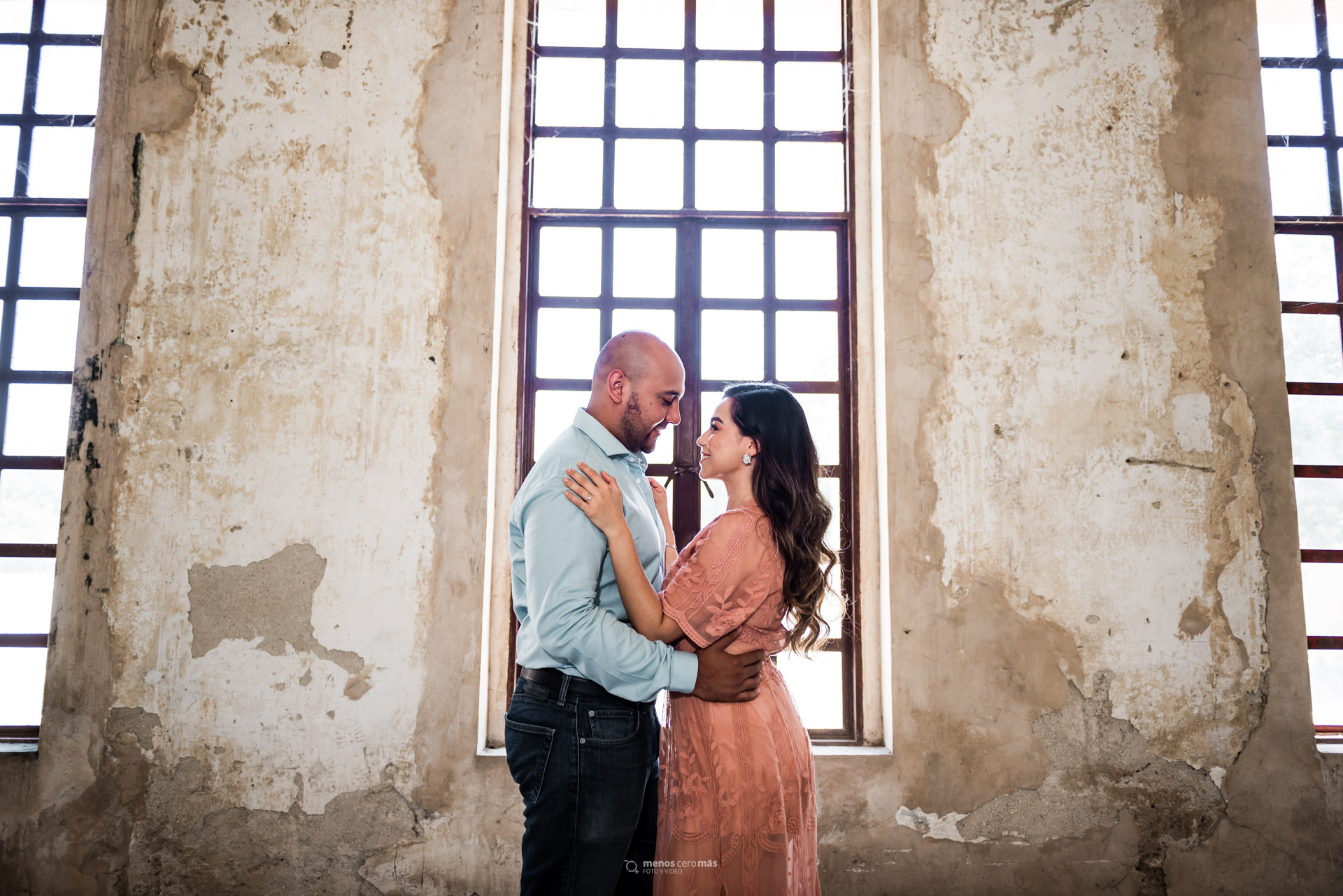 Sesión casual de novios en Monterrey. Novios frente a ventanal en fábrica El Porvenir