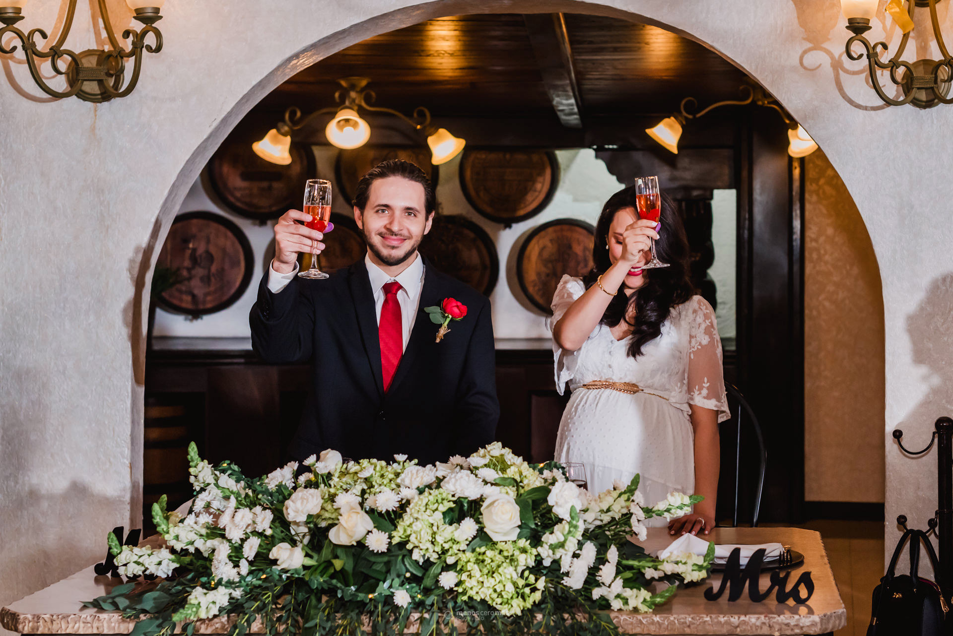 Fotografía de Johanna y Adrián brindando en su boda civil celebrada en Las Pampas Eventos, en Monterrey, México. Johanna, vestida con un vestido blanco, sonríe y mira a Adrián, quien la mira con amor.