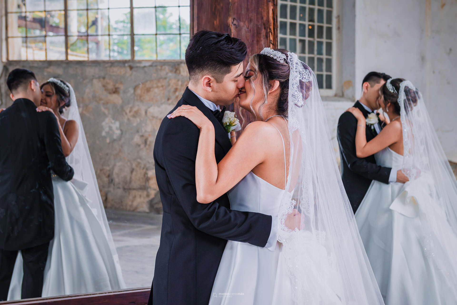 Imagen de una pareja de novios abrazados y besándose en la Fábrica El Porvenir, con sus reflejos visibles en dos espejos detrás de ellos. La imagen fue tomada en Santiago, N.L. Su boda se realizo en Hacienda M.