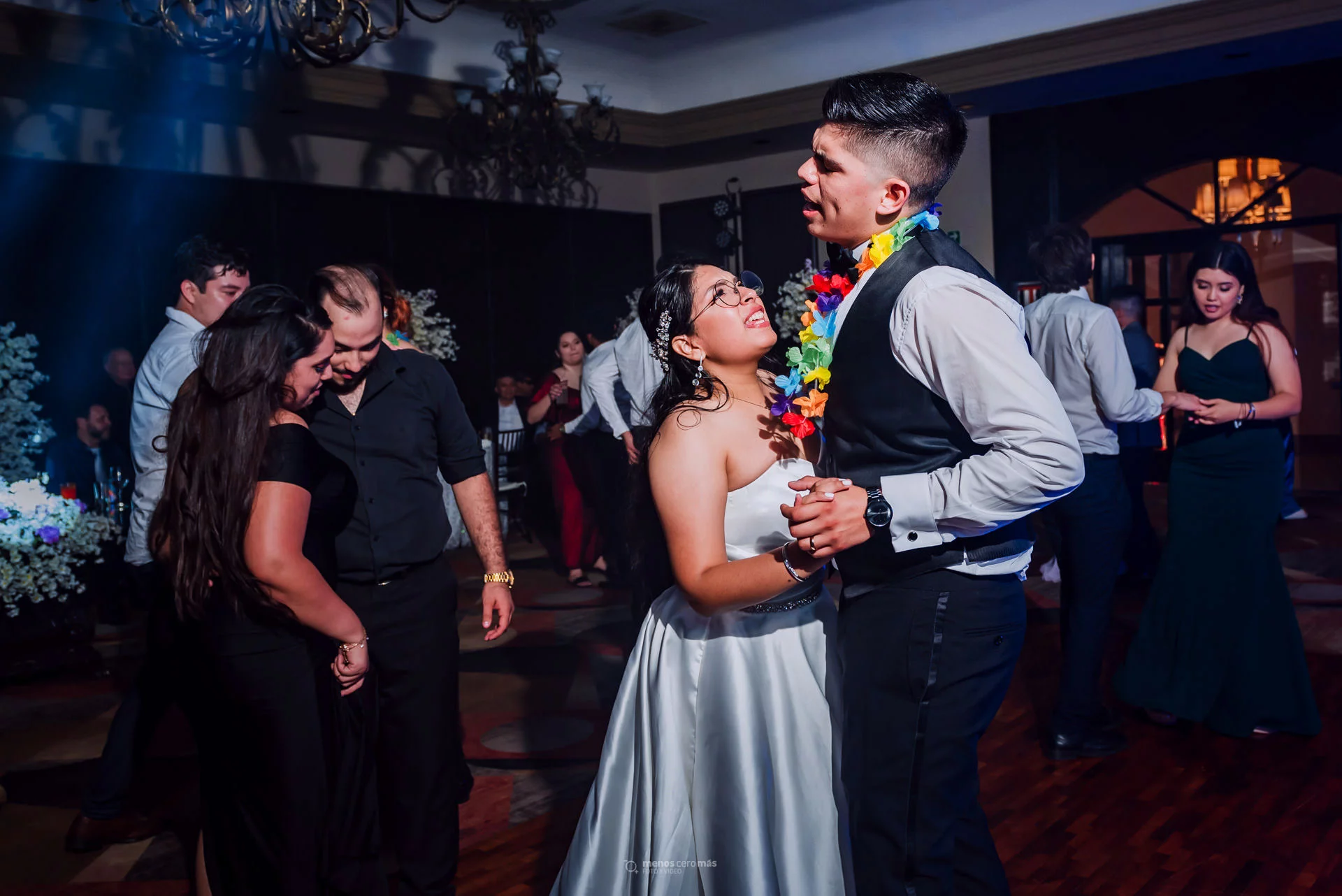 Fotografía de Lilian y Jesús bailando emocionados durante su boda en Las Pampas Eventos, en Monterrey, México. Lilian, con un vestido de novia blanco, sonríe radiante mientras sostiene la mano de Jesús, quien también lleva traje. Ambos bailan con alegría y felicidad, celebrando su amor recién adquirido.